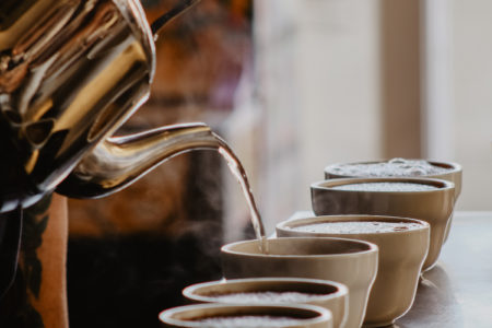 a row of cups being filled from a kettle