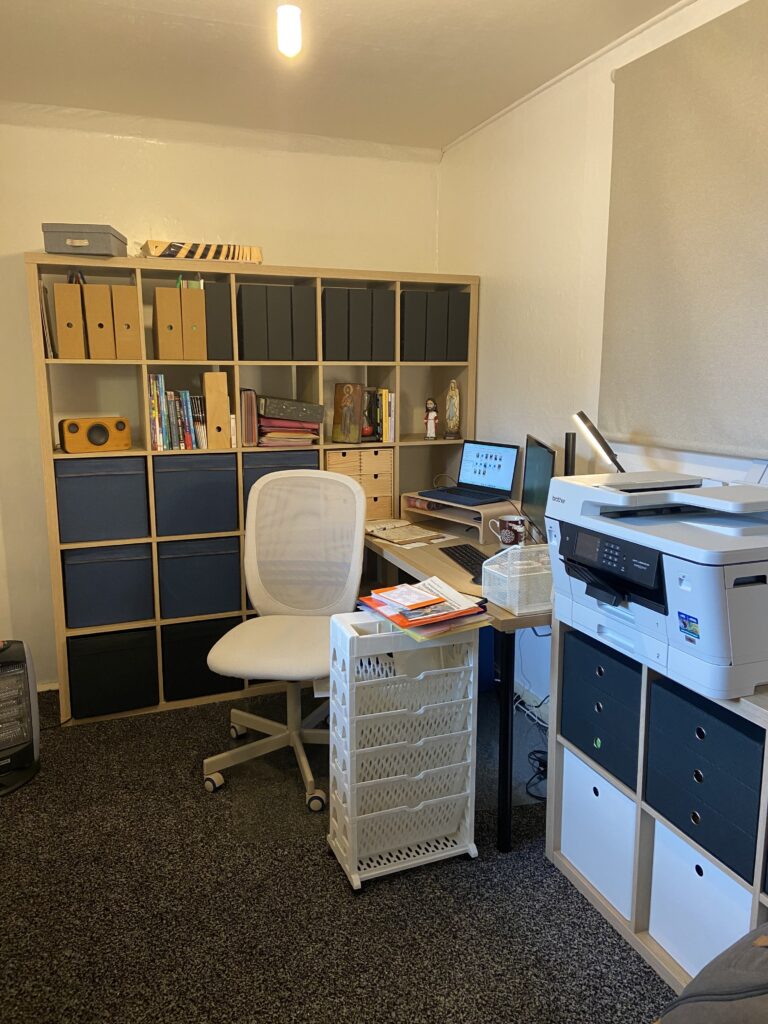 An office with shelves, a printer, desk and office chair