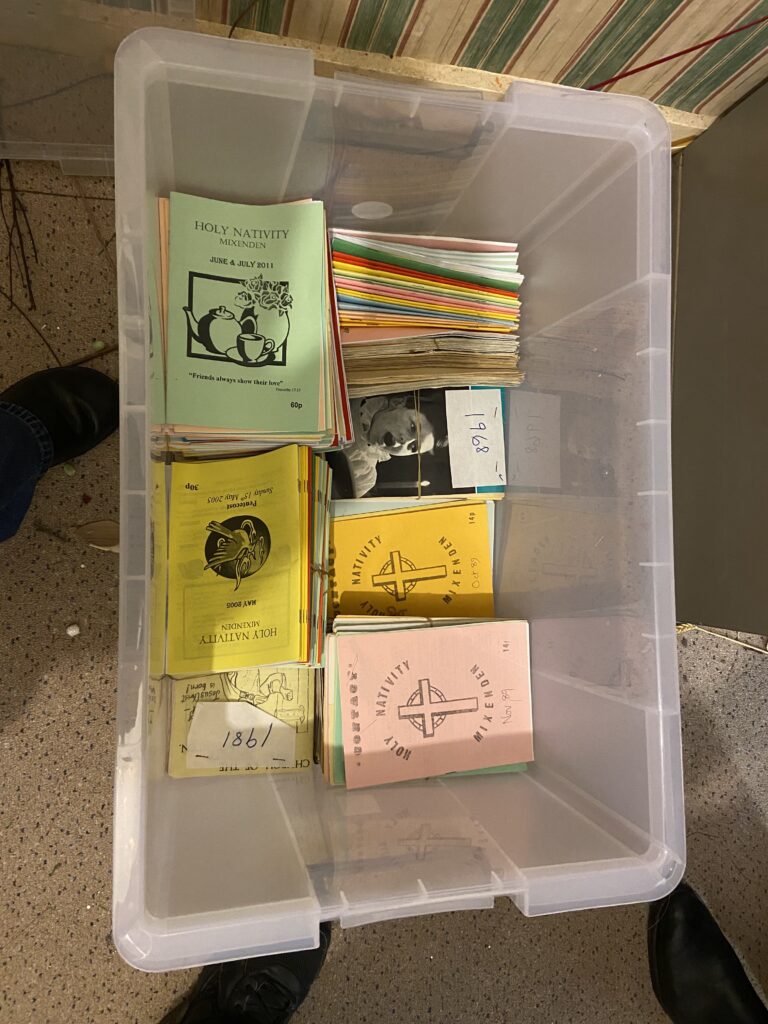A plastic box full of A5 folded paper magazines in various colours and designs